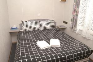a black and white bed with two white towels on it at Smugglers Cove Holiday Village in Forster