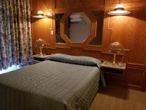 a bedroom with a bed and a mirror and two lamps at New Imperial Inn in Cold Lake +12 photos