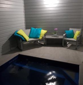 two benches with pillows sitting next to a swimming pool at ChEZ MAYAH in Le Gosier