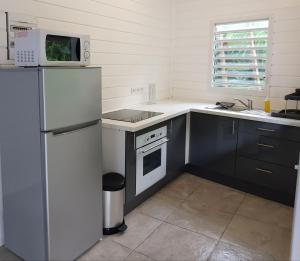 a kitchen with a refrigerator and a stove and a microwave at ChEZ MAYAH in Le Gosier