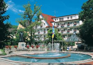 a fountain in front of a building with a statue at Kurhotel Roswitha in Bad Wörishofen
