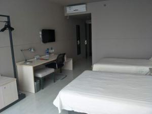 a hotel room with two beds and a desk with a computer at Jinjiang Inn Xi'an Exhibition Centre Zhangba East Road in Xi'an