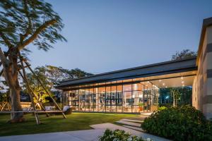 a large building with glass windows and a swing at The Rain Cha-am Huahin By Thanon in Cha Am