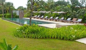 - une piscine avec des chaises longues et des parasols dans l'établissement Sala Lodges, à Siem Reap
