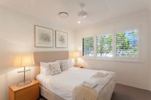 a bedroom with a white bed and two windows at Noosa Shores Resort in Noosa Heads