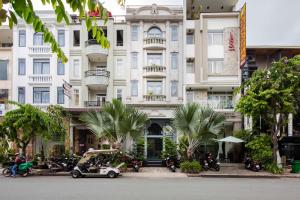 a white building with palm trees in front of it at Vien Dong Hotel 2 in Ho Chi Minh City