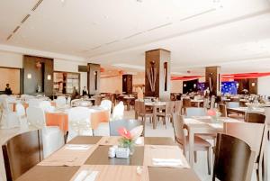 a restaurant with white tables and white chairs at Permai Hotel Kuala Terengganu in Kuala Terengganu