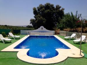 a swimming pool in a yard with two lawn chairs at Casa Rural Villa Mara in La Puebla de los Infantes