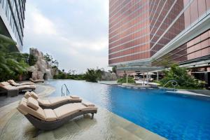 a hotel swimming pool with lounge chairs and buildings at The Trans Luxury Hotel Bandung in Bandung