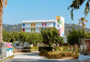 un gran edificio blanco con árboles delante de él en Càmping Bellsol, en Pineda de Mar