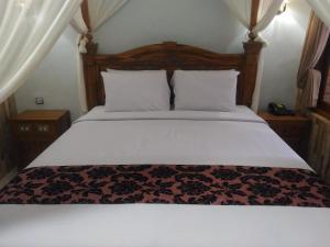 1 dormitorio con 1 cama grande y cabecero de madera en Hotel Sorga Cottages, en Kuta