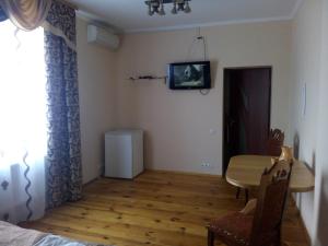 a room with a table and a tv on the wall at Oselya Guest House in Yahotyn