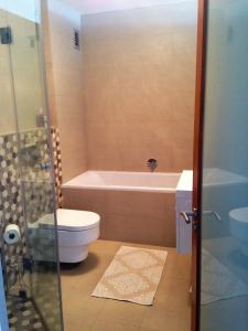 a bathroom with a tub and a toilet and a sink at Beachfront Apartment at Seaspray in Blouberg in Bloubergstrand