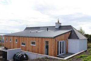 een groot houten huis met een dak bij 35 Newvalley in Stornoway