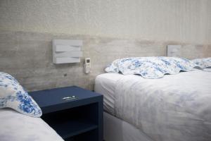 a bedroom with two beds with blue and white pillows at Hotel Dois Irmãos in Curitiba