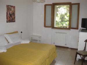 ウルビーノにあるCountry House-B&B-Appartamenti Ai Cipressiのベッドルーム1室(黄色のベッドカバー付)、窓が備わります。