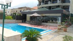 a swimming pool with chairs and an umbrella next to a building at Holiday Suites Hotel & Beach Resort in Jounieh