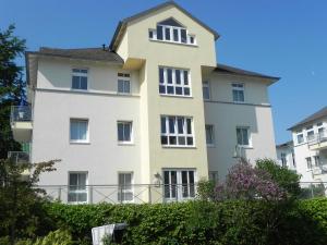ein hohes weißes Gebäude mit einem Dach in der Unterkunft Ferienwohnung 3 26 Inselstrand in Ahlbeck