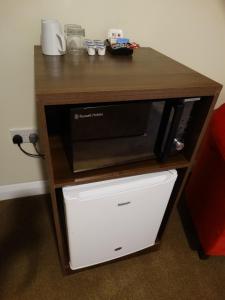 a wooden table with a microwave oven on a shelf at Trivelles Seaforth in Bootle
