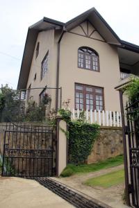a white house with a gate and a fence at Perera Homestay in Nuwara Eliya