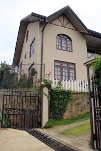 une maison blanche avec un portail et une clôture dans l'établissement Perera Homestay, à Nuwara Eliya