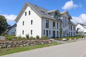 a white house with black windows and a stone wall at Haus Windrose Whg. 9 Seestern in Thiessow
