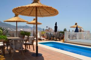 un patio con sombrillas y una piscina en Villa Carabeo Playa, en Nerja