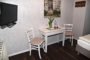 Zimmer mit einem Tisch und Stühlen sowie einem TV in der Unterkunft Hartlef´s Gasthof in Stade