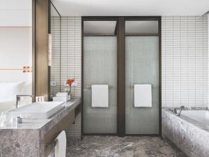 a bathroom with a tub and a sink and two mirrors at Cordis Shanghai Hongqiao (Langham Hospitality Group) in Shanghai
