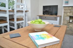 um livro sentado numa mesa com uma tigela de maçãs em Riverside Cottage em Wetherby