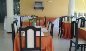 a dining room with tables and chairs with orange table cloth at Pousada Cardoso in Ipiaú