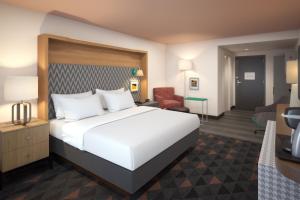 Holiday Inn & Suites Decatur-Forsyth, an IHG Hotel في ديكاتور: غرفة نوم بسرير ابيض وغرفة معيشة