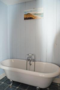 a white bath tub in a bathroom with a painting at Scenery Cottage in Bridford