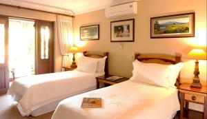 a hotel room with two beds and a window at The Woodpecker Inn in Pretoria