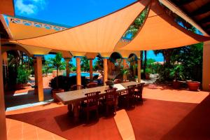 un patio con mesa y sillas bajo una sombrilla grande en Goood Resort, en Kralendijk