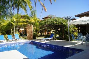 a pool with chairs and umbrellas next to a house at Pousada Paisagem in Paraty