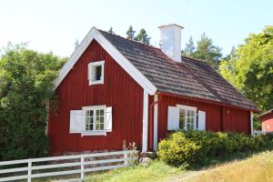 a red barn with a white fence in front of it at Rösjöbaden Camping & Stugby in Sollentuna