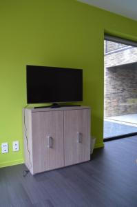 a flat screen tv on a wooden cabinet in a room at Bed & Zorg Ypres in Ieper