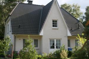 ein weißes Haus mit schwarzem Dach in der Unterkunft Ferienhaus Dierhagen Strand I & II in Dierhagen