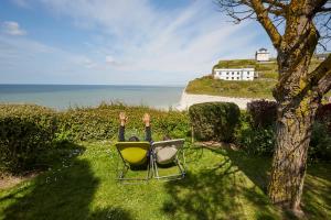 two people laying in chairs looking at the ocean at The Originals Hôtel Le Cise Restaurant Chambres et Suites in Ault