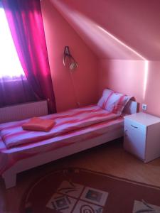 a bedroom with a bed in a pink room at Becze Vanda kulcsosház in Lăzarea