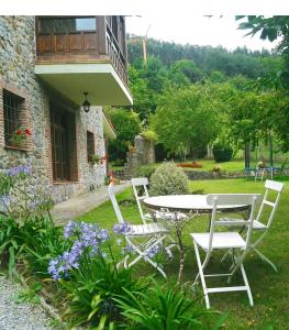 two white chairs and a table in a garden at Finca Artienza in Ramales de la Victoria