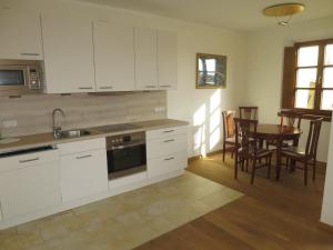 a kitchen with white cabinets and a table and chairs at Ferienwohnung am Blasturm in Schwandorf in Bayern