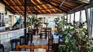 un restaurante con mesas, sillas y plantas en Amanda Hotel en Karlovasi