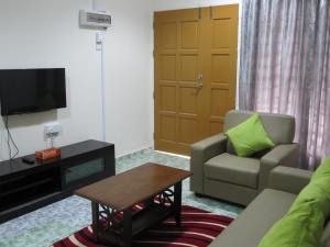 uma sala de estar com um sofá e uma cadeira e uma televisão em Al-Kahfi Homestay em Dungun