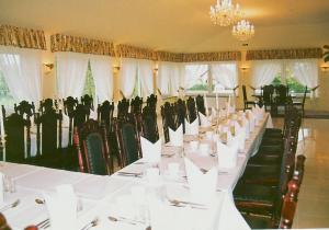 a long dining room with white tables and green chairs at Zajazd Kosynier in Węgrzce