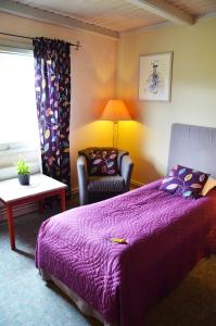 a bedroom with a purple bed and a chair at Jämtkrogen Hotell in Bräcke
