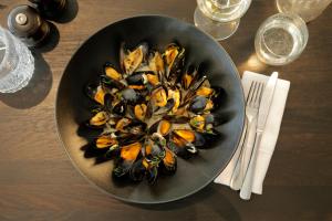 a black plate of mussels on a wooden table at Park Central Hotel in Bournemouth