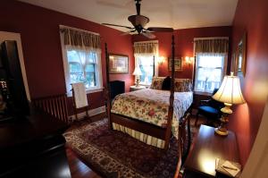 a bedroom with red walls and a bed and windows at The Oliver Inn in South Bend
