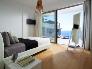 Beachfront Villa in Crete - Epavli Luxury Villa في أغيا بيلاغيا: غرفة نوم مع سرير وإطلالة على المحيط
